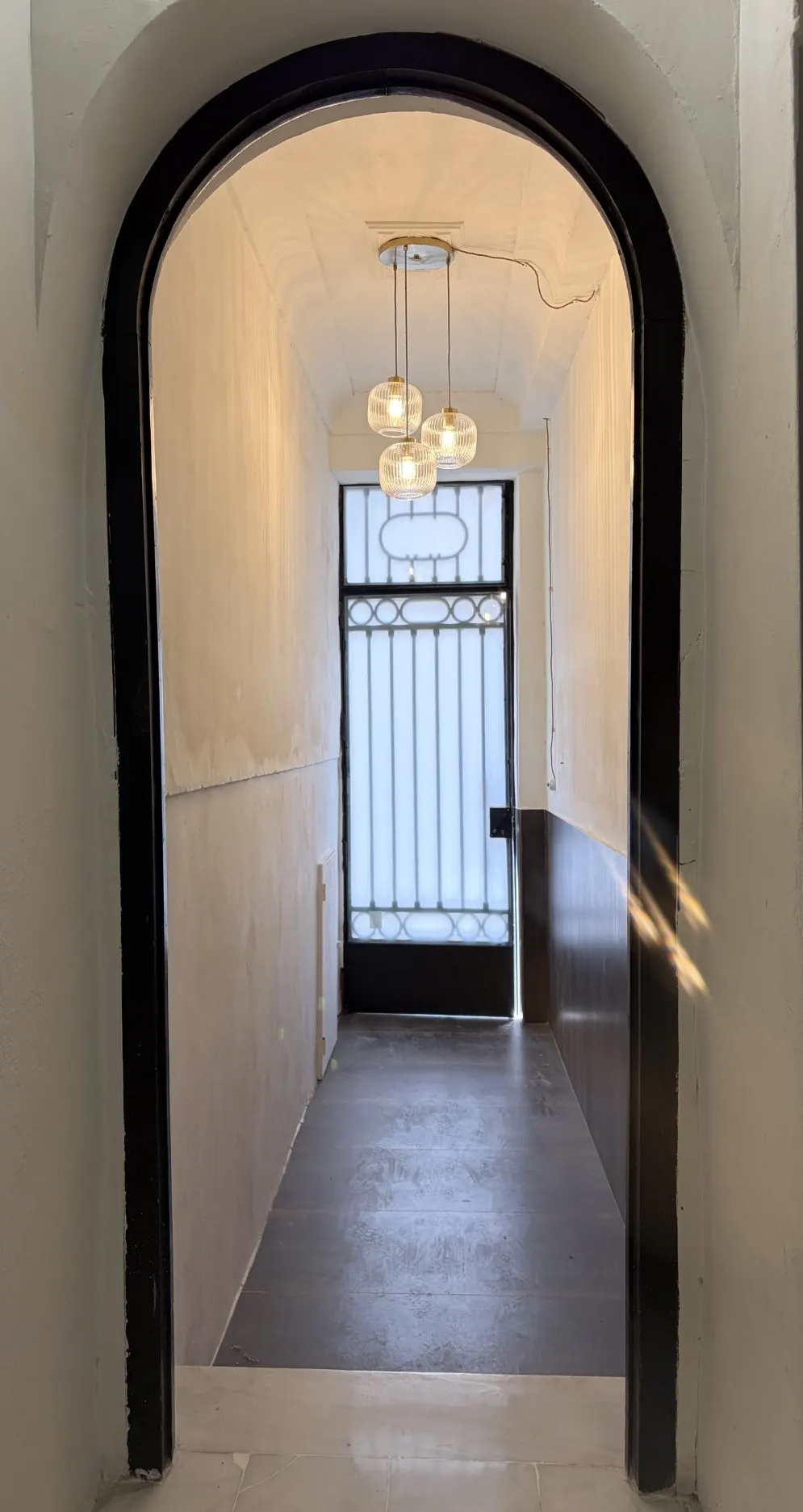 Entrada de Greenhome Troneta, con arco original y lámparas colgantes